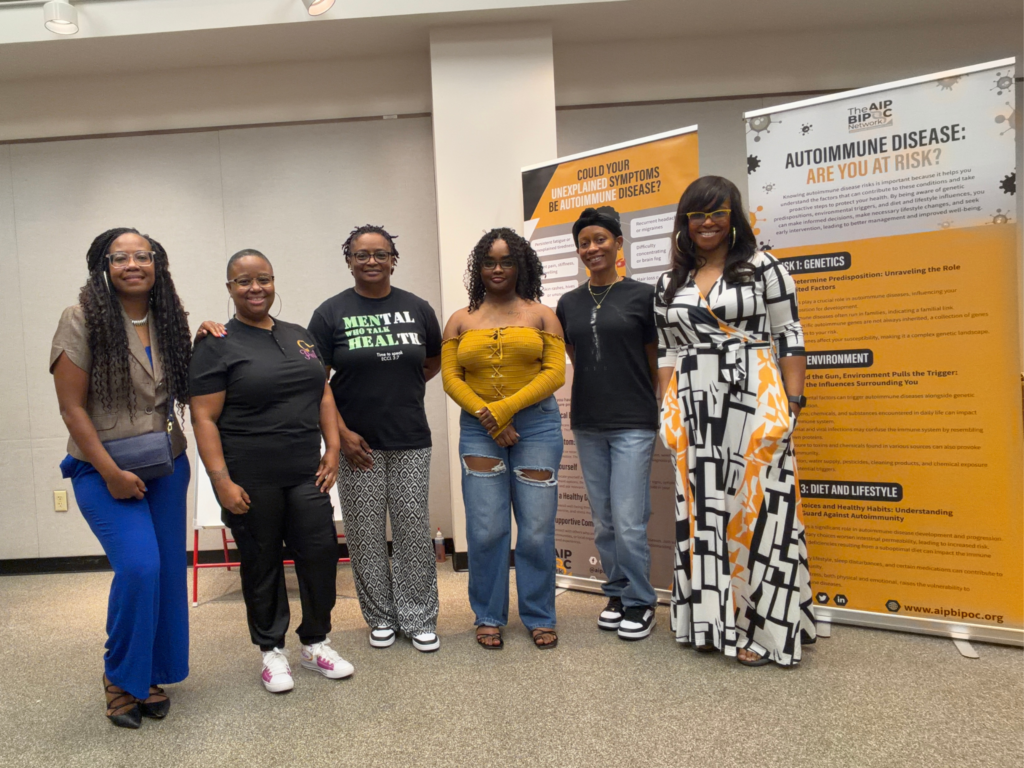 Group photo of The AIP BIPOC Network and Positive Express following the Worthy Beyond the Flare workshop, standing in front of autoimmune education displays.